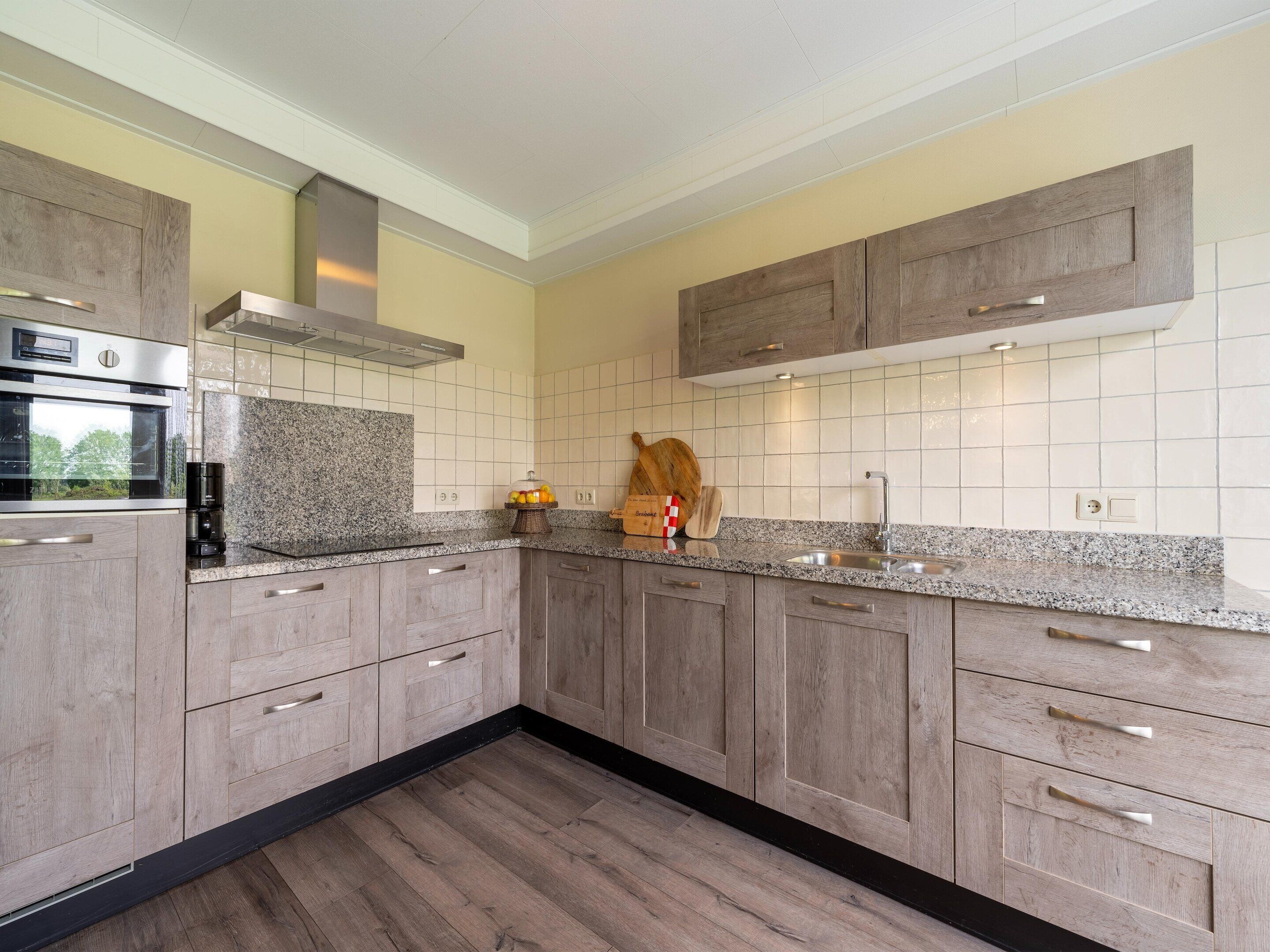 A modern kitchen with wooden cabinets, granite countertops, and a stainless steel sink.