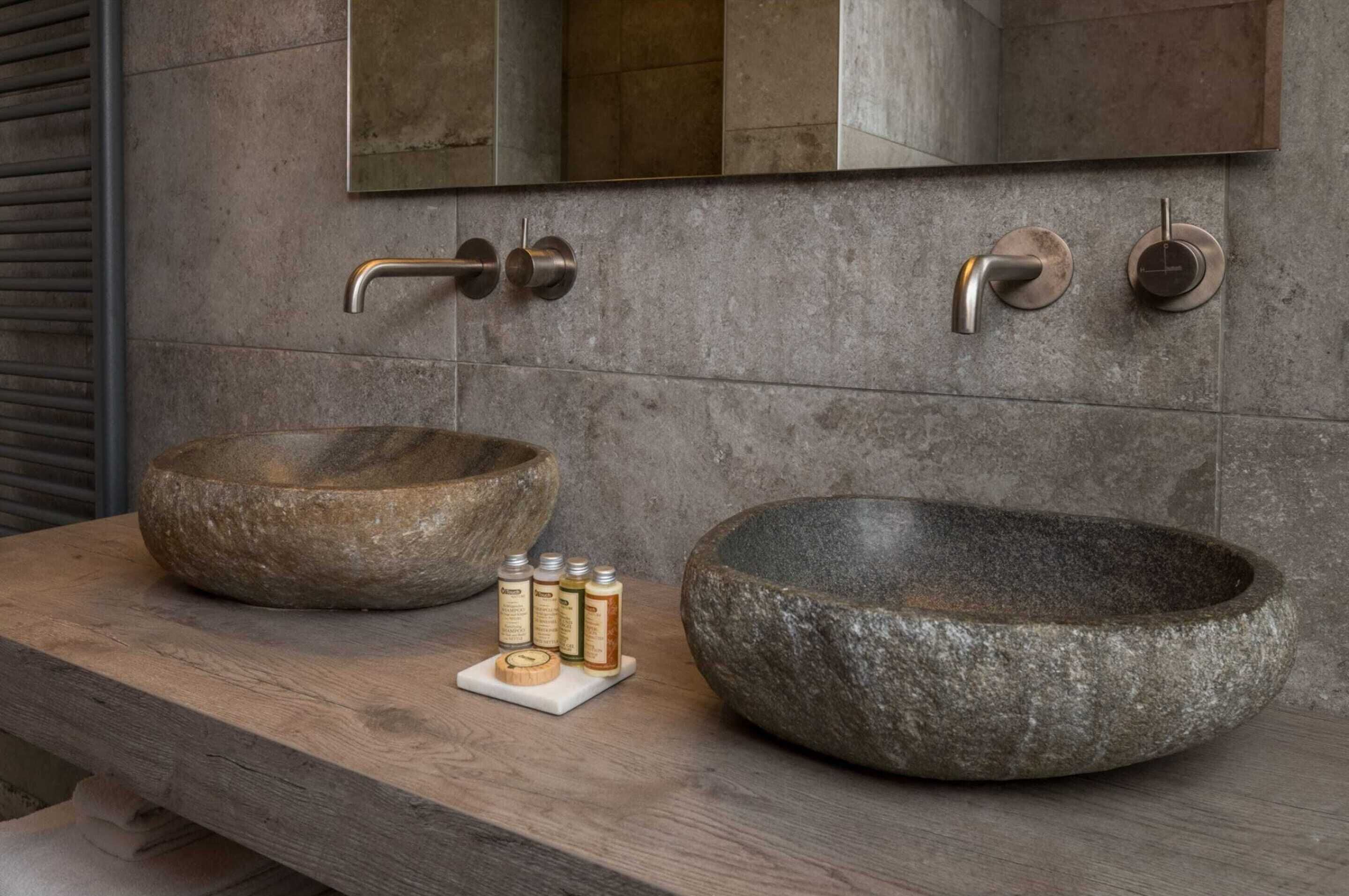 Un baño con dos lavamanos de piedra, una encimera de madera y un espejo arriba.