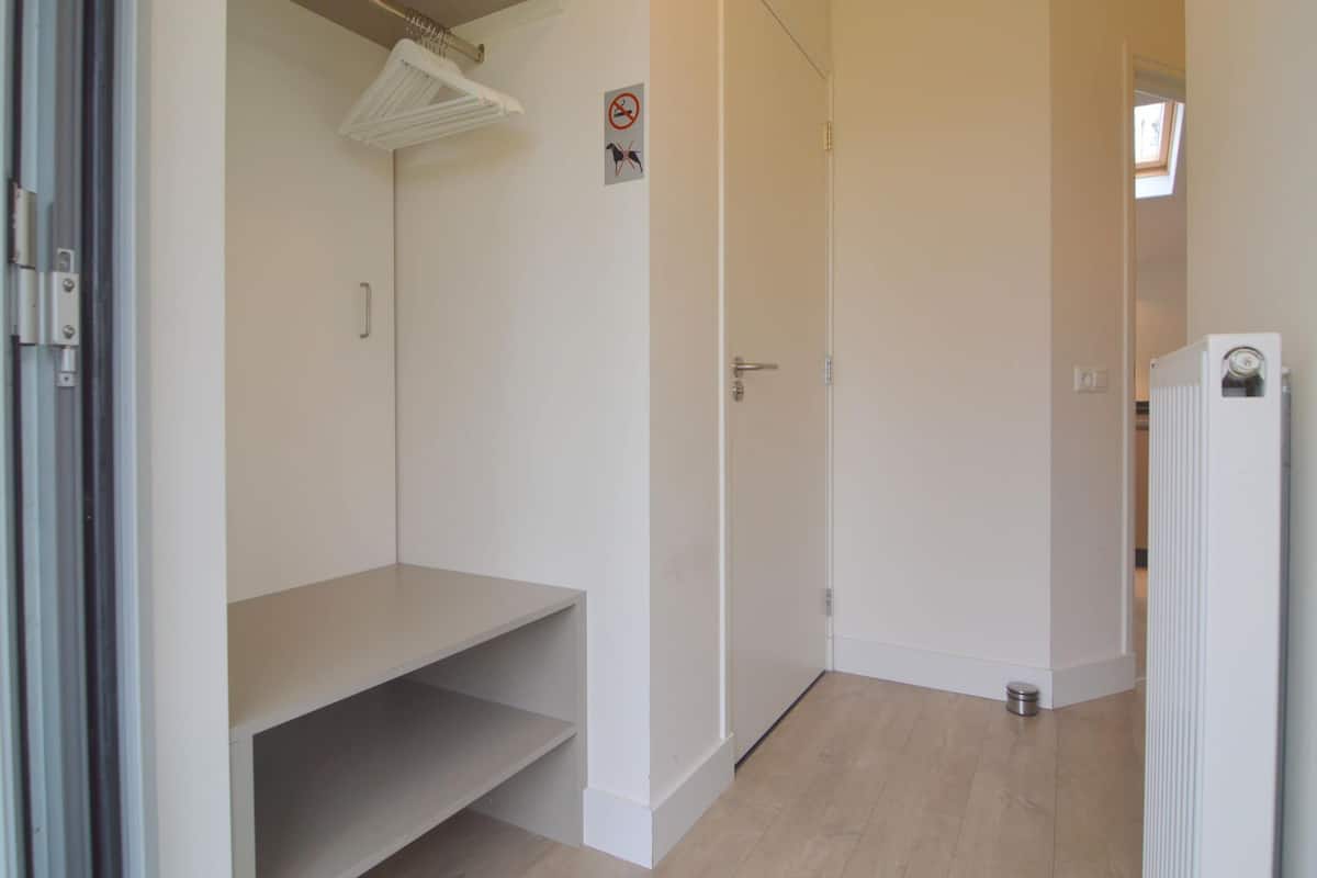 A hallway with a white radiator, a door with a handle, and a no-smoking sign on the wall.