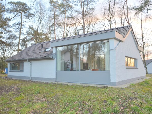 A modern, single-story house with large windows and a sloped roof, surrounded by trees. - Alluring Holiday Home in Limburg Near Forest (Stramproy)