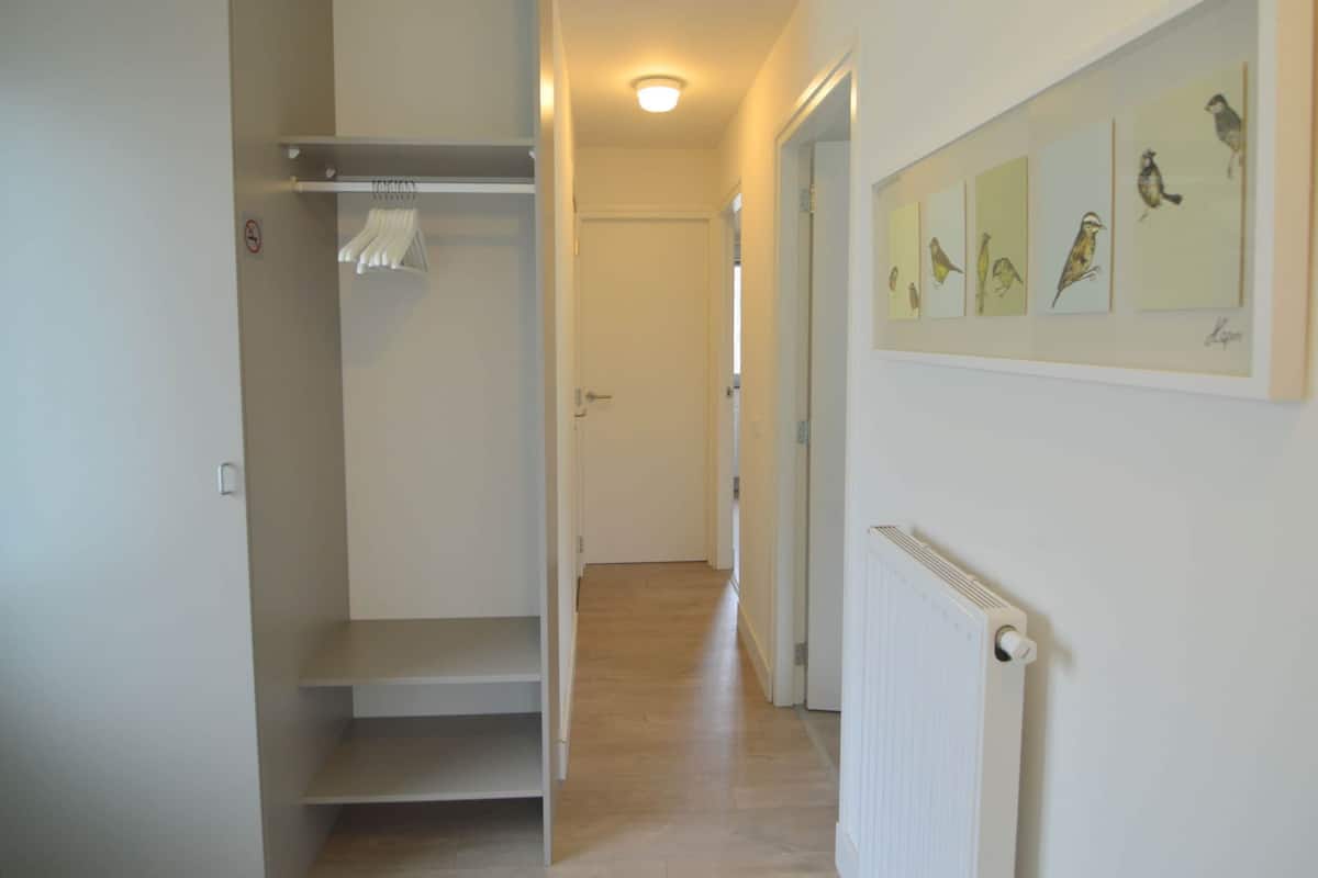 A hallway with a white door, a radiator, and a wall with bird illustrations.