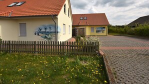 A residential area with two houses, one with a mural on the side, a wooden fence, and a cobblestone path. - Modern Holiday Home in Boiensdorf Near Sea (Boiensdorf)