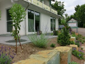 A modern building with large windows, a well-maintained garden with various plants and flowers, and a sign indicating it is a retirement home. - Modern Apartment in Schwalefeld With Garden (Willingen)