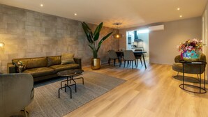 A modern living room with a leather sofa, a coffee table, and a dining area with chairs and a table. - Appealing Apartment in Domburg Near the Beach (Domburg)