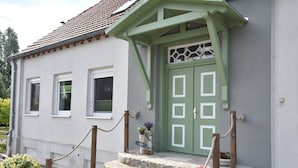 A building with a green door, white-framed windows, stone steps, and a rope barrier. - Comfortable Apartment Near Insel Poel (Blowatz)
