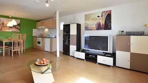 A modern kitchen with a dining area, a glass-top coffee table, and a flat-screen TV. - Comfortable Apartment Near Insel Poel (Blowatz)