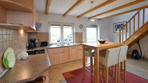 A kitchen with wooden beams, a dining area with a red rug, and a staircase. - Lovely Apartment in Stellshagen With Garden (Damshagen)