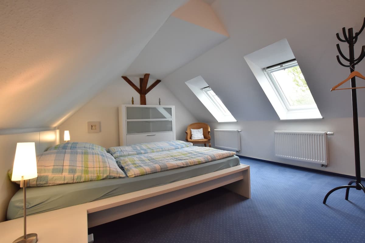 Ein Schlafzimmer mit Hochbett, Dachfenstern, Heizkörper und Kleiderhaken.