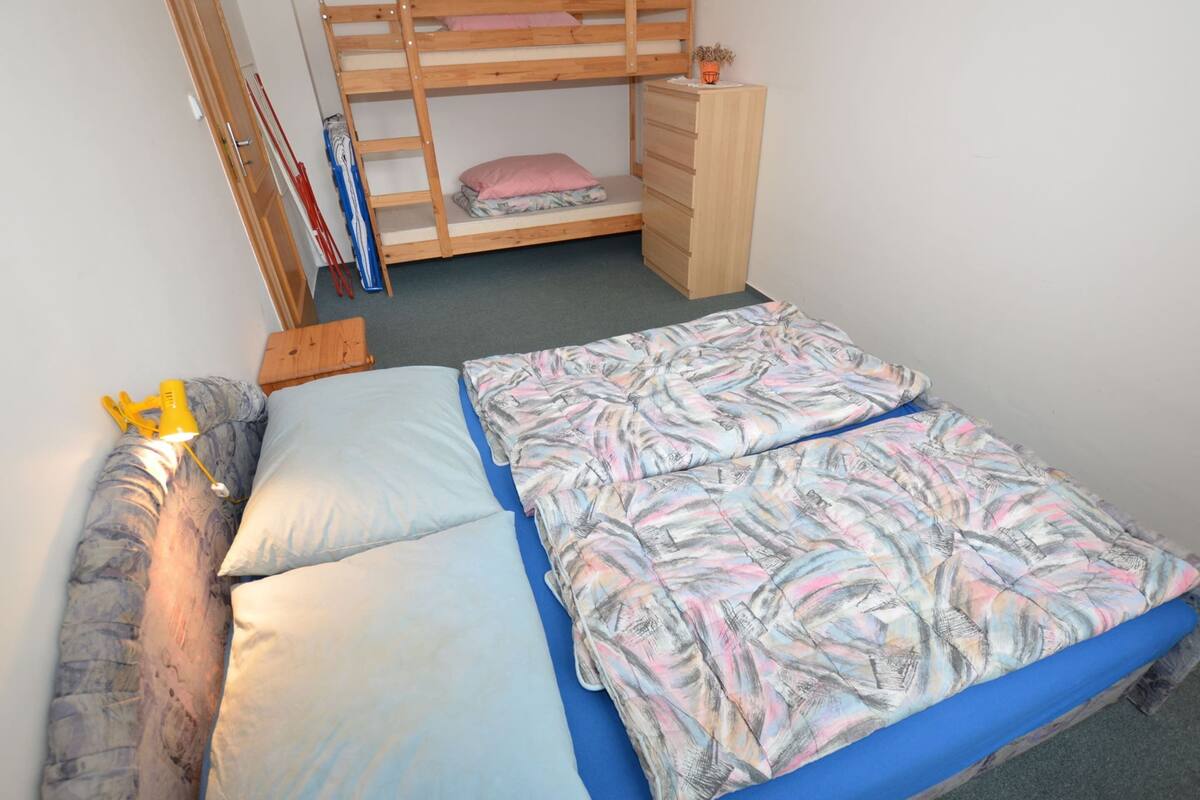 A bunk bed with a wooden ladder, a desk, and a chair.