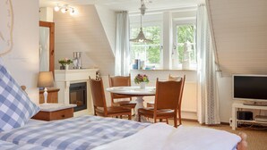 Une chambre à coucher avec un lit, un bureau et une chaise, une télévision et une fenêtre avec des rideaux.