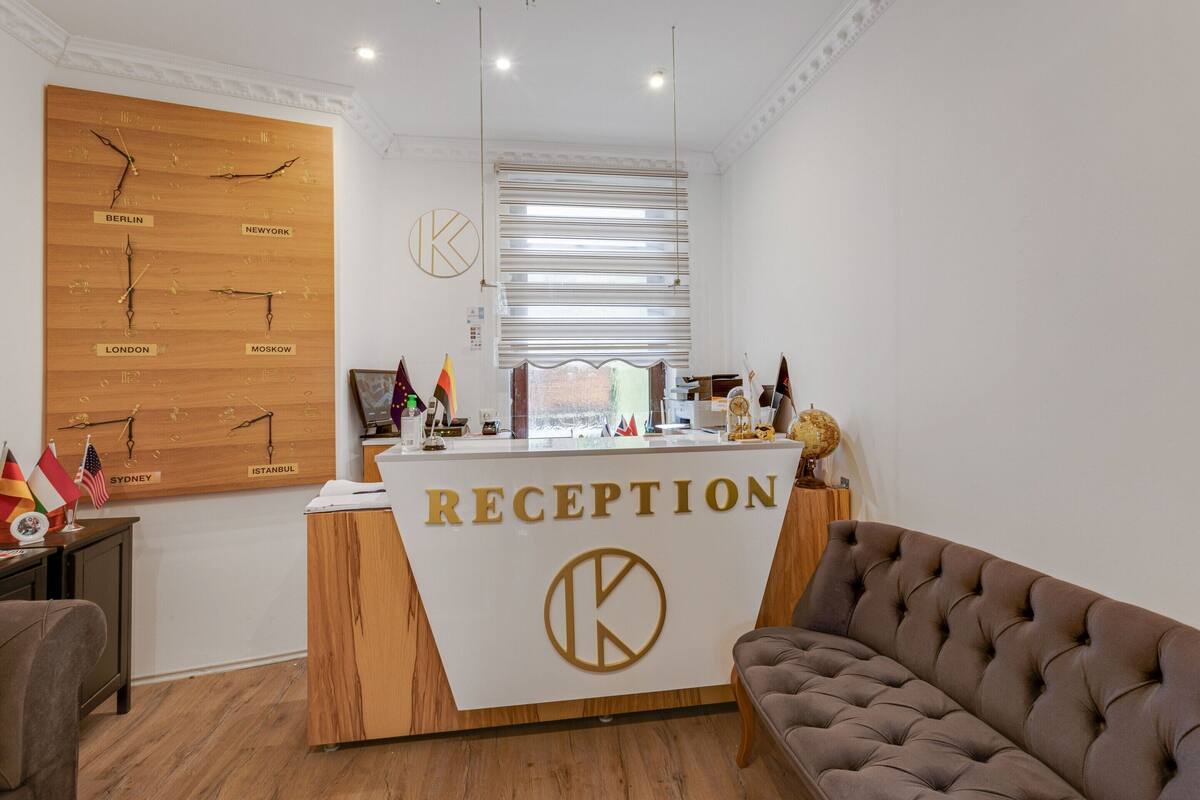 Un mostrador de recepción con un cartel que dice "RECEPTION" y un reloj de pared que muestra la hora en varias ciudades.