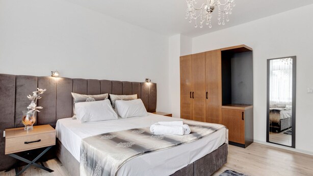 A modern bedroom with a large bed, wooden wardrobe, and a mirror. - Pleasant Apartment in Oberhausen With a Terrace (Oberhausen)