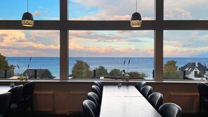Un restaurant amb vistes al mar, grans finestres i seients de cuir.