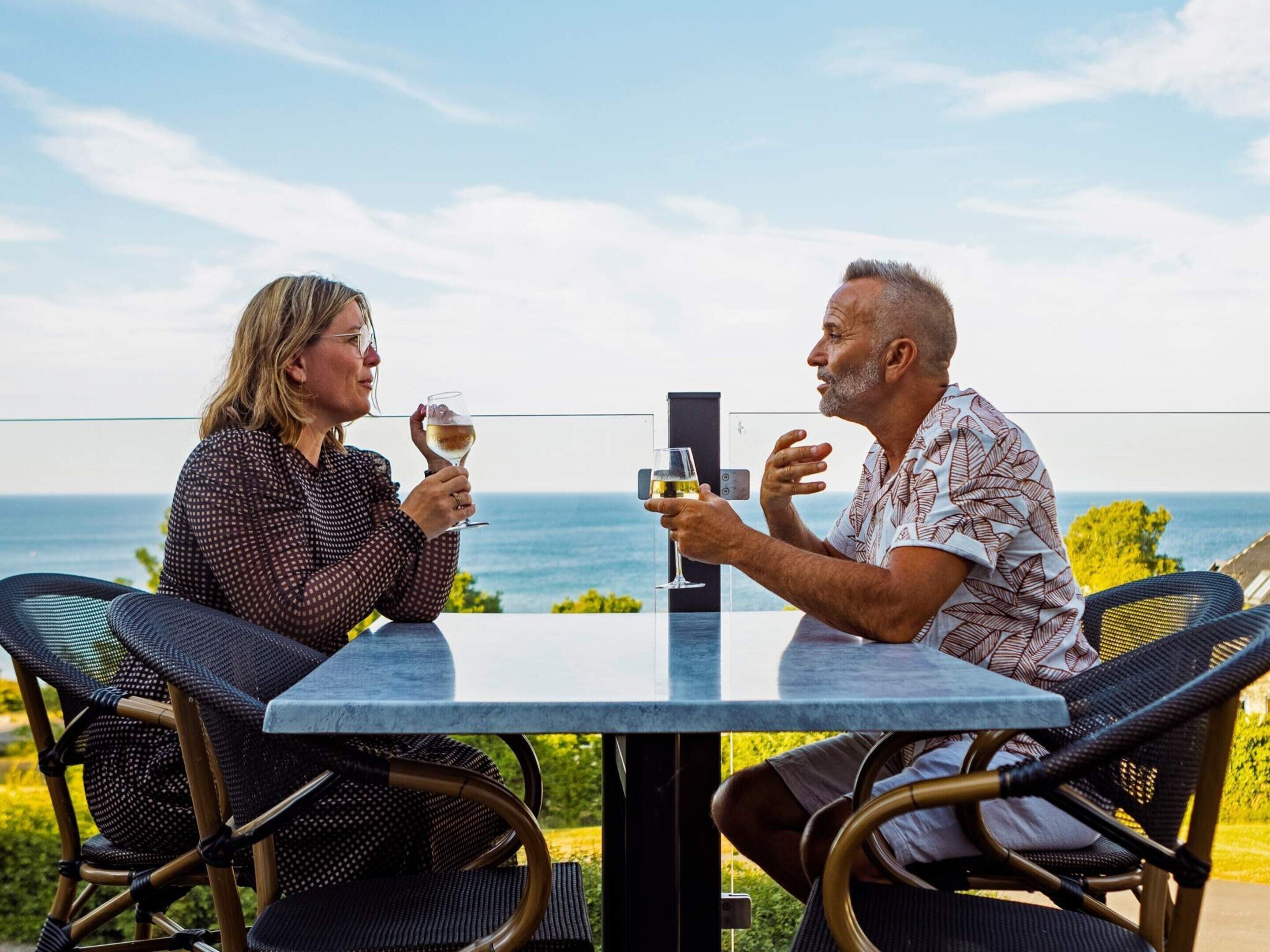 Two people sitting at a table with a view of the ocean.