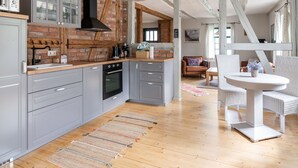 A modern kitchen with grey cabinets, a brick wall, and a wooden floor. - Lovely Holiday Home in Zierow With Terrace (Zierow)