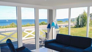 A modern room with large windows, a blue sofa, a white table, and a chair.