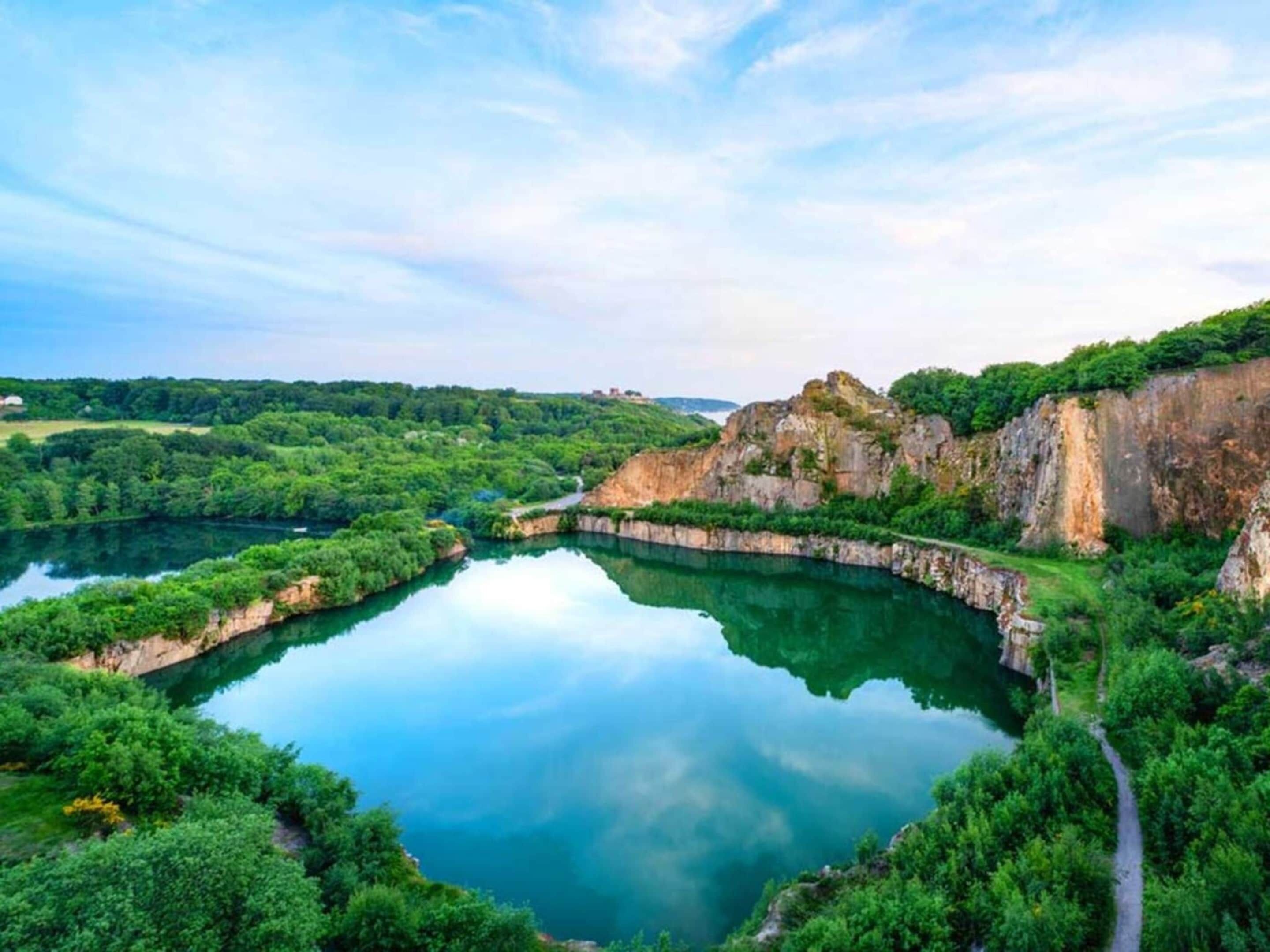 Un lago tranquilo rodeado de exuberante vegetación y escarpados riscos.