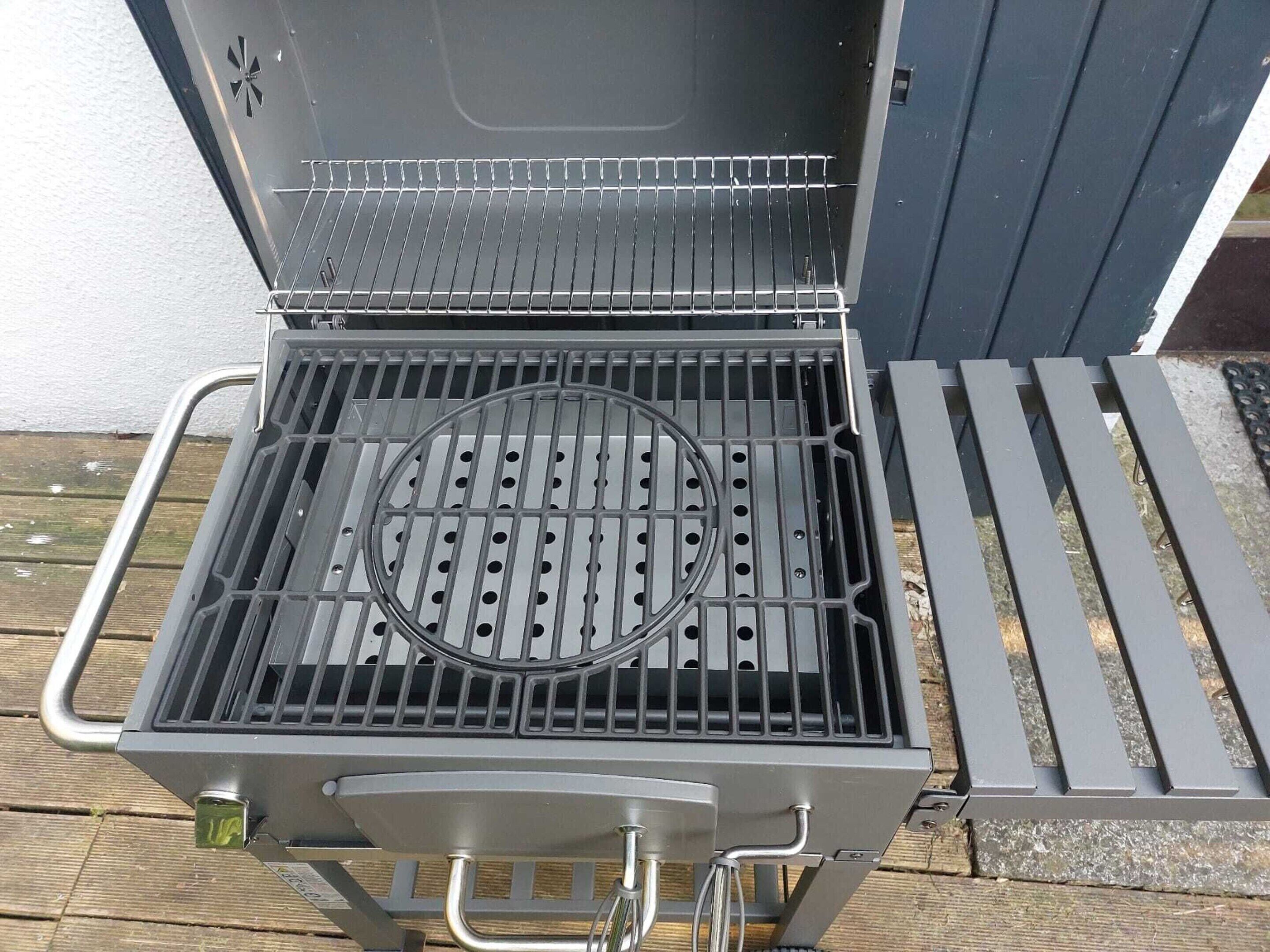 A barbecue grill with a metal grate, a circular vent, and a handle.