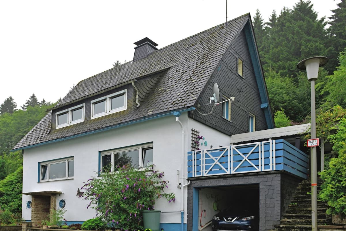 Ein zweistöckiges Haus mit Garage, Satellitenschüssel und einem Auto im Inneren.