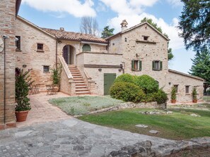 A stone building with a staircase leading to a door, surrounded by greenery and potted plants. - Stunning Apartment in Mombaroccio Near Metauro River (Mombaroccio)