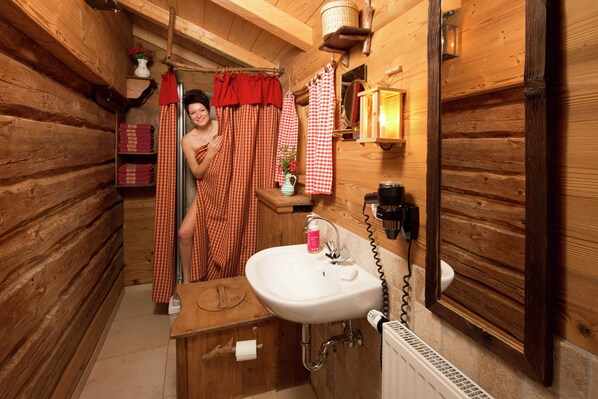 A wooden cabin bathroom with a sink, mirror, and red and white checkered curtains. - Eco-friendly Chalet Near the Lake in Asten (Tittmoning)
