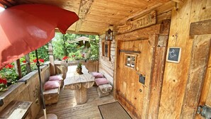 Een houten chalet met een overdekt terras, een houten deur met een bordje en een klein raam.
