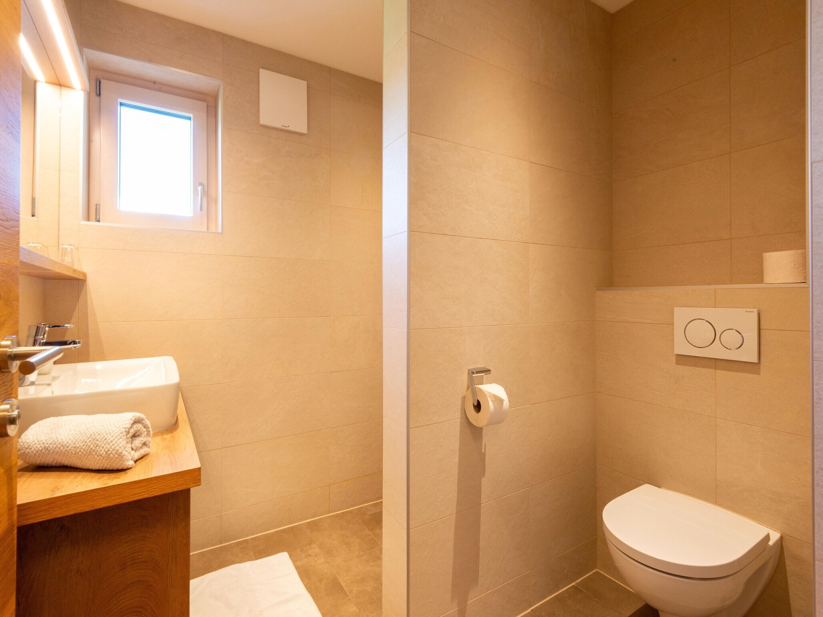 A bathroom with a sink, mirror, towel, toilet, and shower.