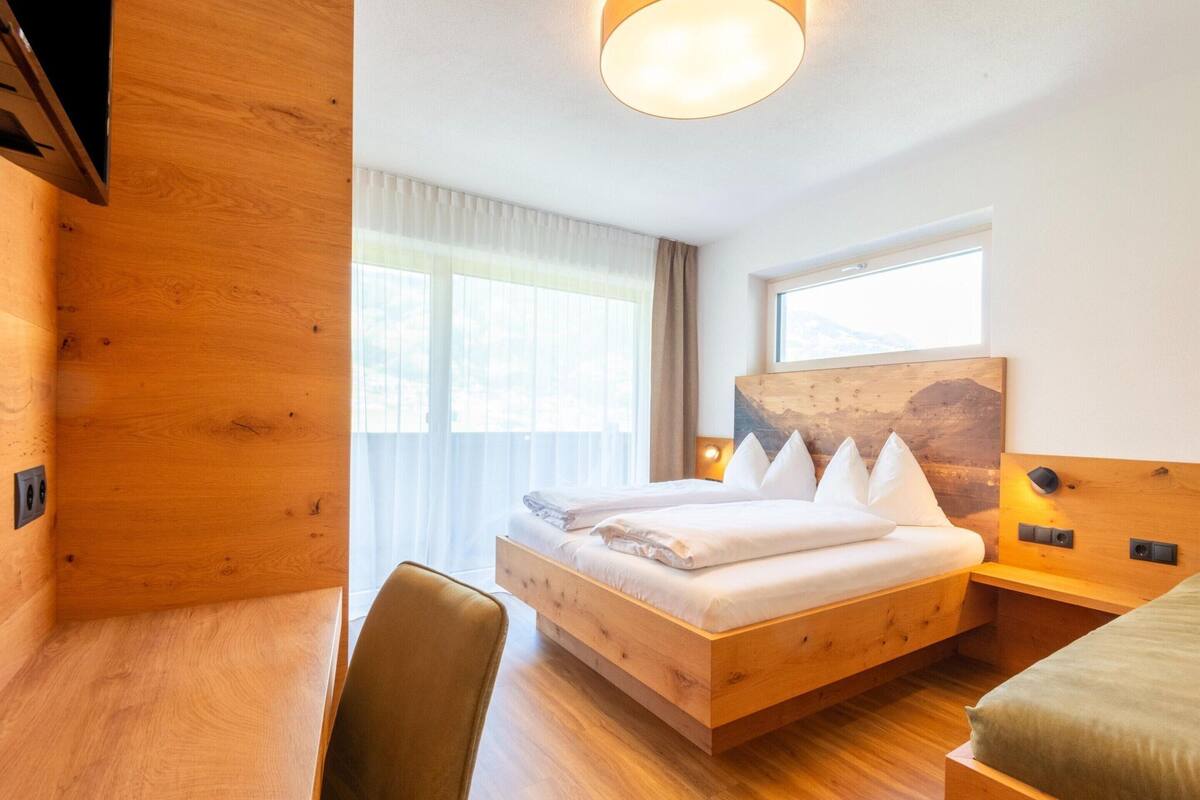 Ein modernes Hotelzimmer mit einem hölzernen Bett, einem Schreibtisch und einem Stuhl.