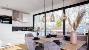 A modern kitchen with a dining area, large windows, and a view of the outside. - Unique Houseboat on and Around the Sneekermeer (Offingawier)