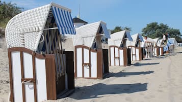 Strandhütten mit gestreiften Markisen, an einer Reihe auf einem Sandstrand platziert.