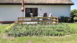 Une maison à toit de chaume avec un jardin devant.