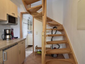 A compact kitchen with a microwave, coffee maker, and wooden staircase. - Cosy Apartment in Pepelow Near Baltic Sea (Am Salzhaff)
