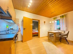 Eine kompakte Küche mit modernen Geräten, ein Essbereich mit Tisch und Stühlen sowie ein Schlafzimmer mit einem Bett.