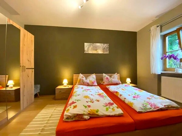 A bedroom with two beds, a wooden wardrobe, a window with curtains, and a painting on the wall. - Comfortable Apartment in Zenting in Lower Bavaria (Zenting)