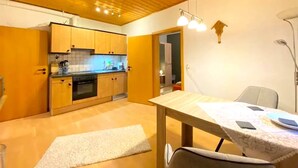 A compact kitchen with wooden cabinets and a dining area with a table and chairs. - Comfortable Apartment in Zenting in Lower Bavaria (Zenting)