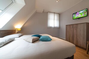 A bedroom with a bed, a television mounted on the wall, a wardrobe, and a window with curtains. - Luxury 8-person Wellness Villa With Sauna and Outdoor hot tub is Unique (Colijnsplaat)
