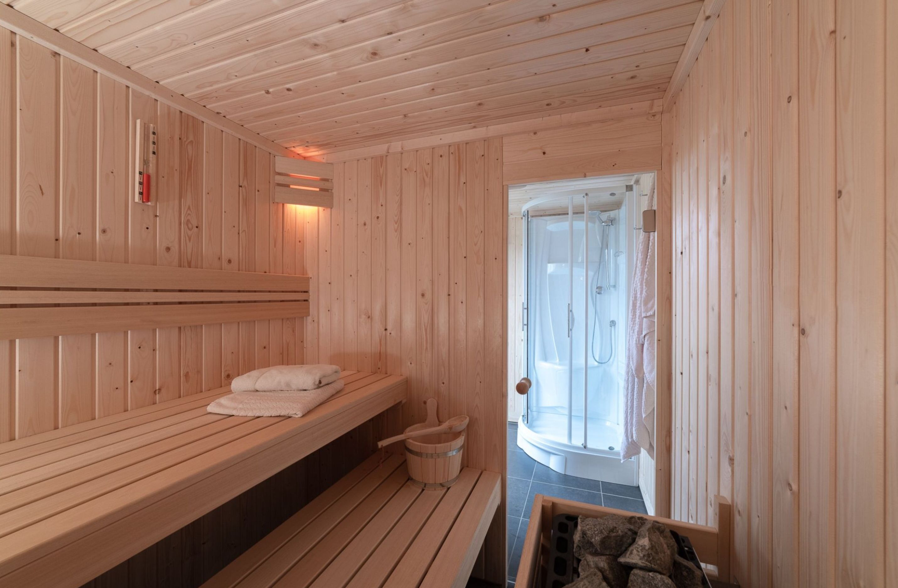 A sauna room with wooden benches and a separate shower area.