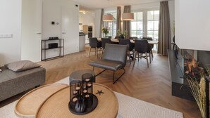 A modern living room with a sofa, a coffee table, and a dining area with chairs and a table. - Luxury 8-person Wellness Villa With Sauna and Outdoor hot tub is Unique (Colijnsplaat)