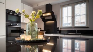 A modern kitchen with a black countertop, a vase with flowers, and candles. - Luxury 8-person Wellness Villa With Sauna and Outdoor hot tub is Unique (Colijnsplaat)