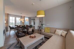 A modern living room with a sofa, coffee table, and dining area. - Luxury 8-person Wellness Villa With Sauna (Colijnsplaat)