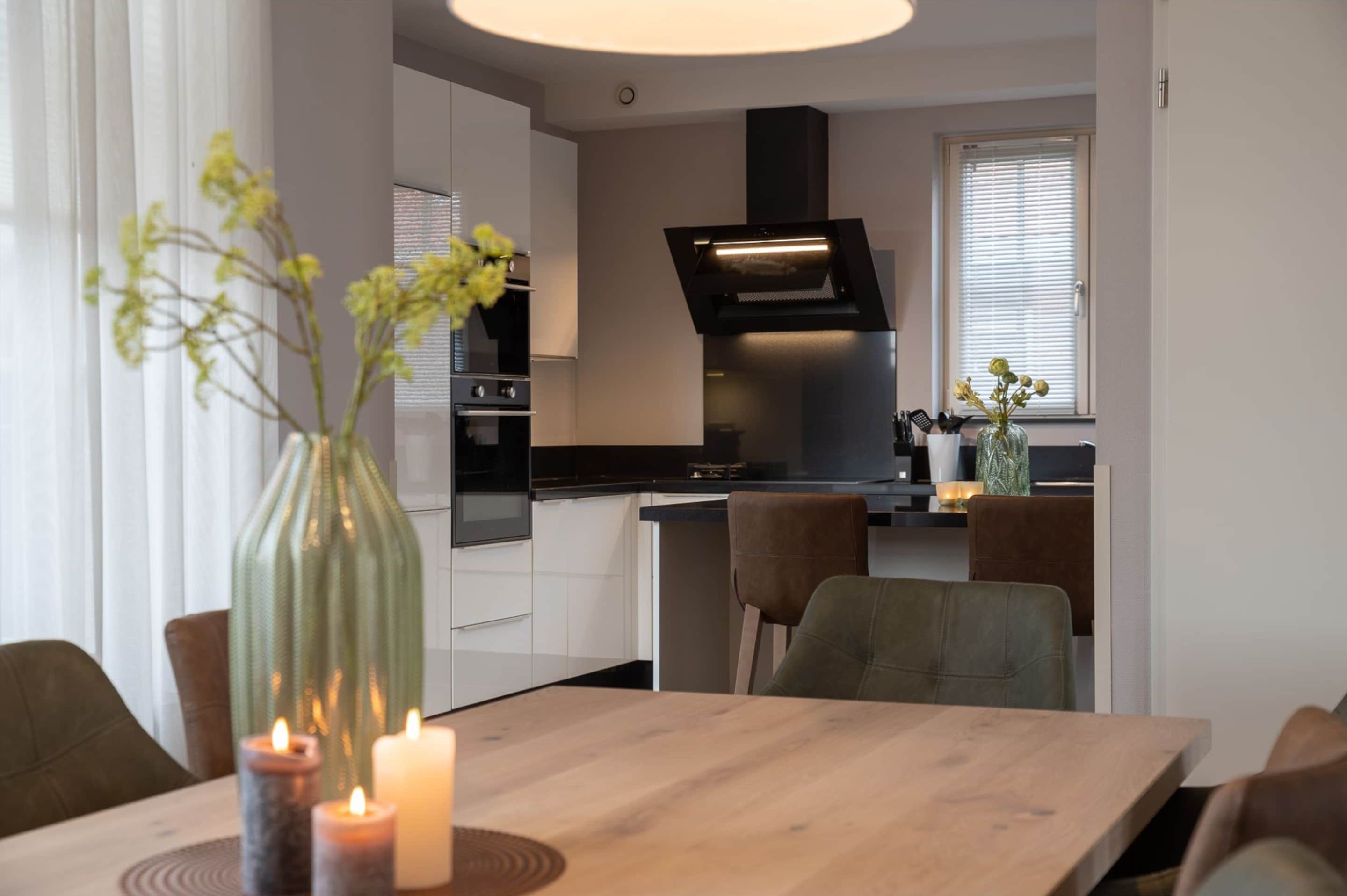A modern kitchen with a central island, built-in oven, and a black range hood.
