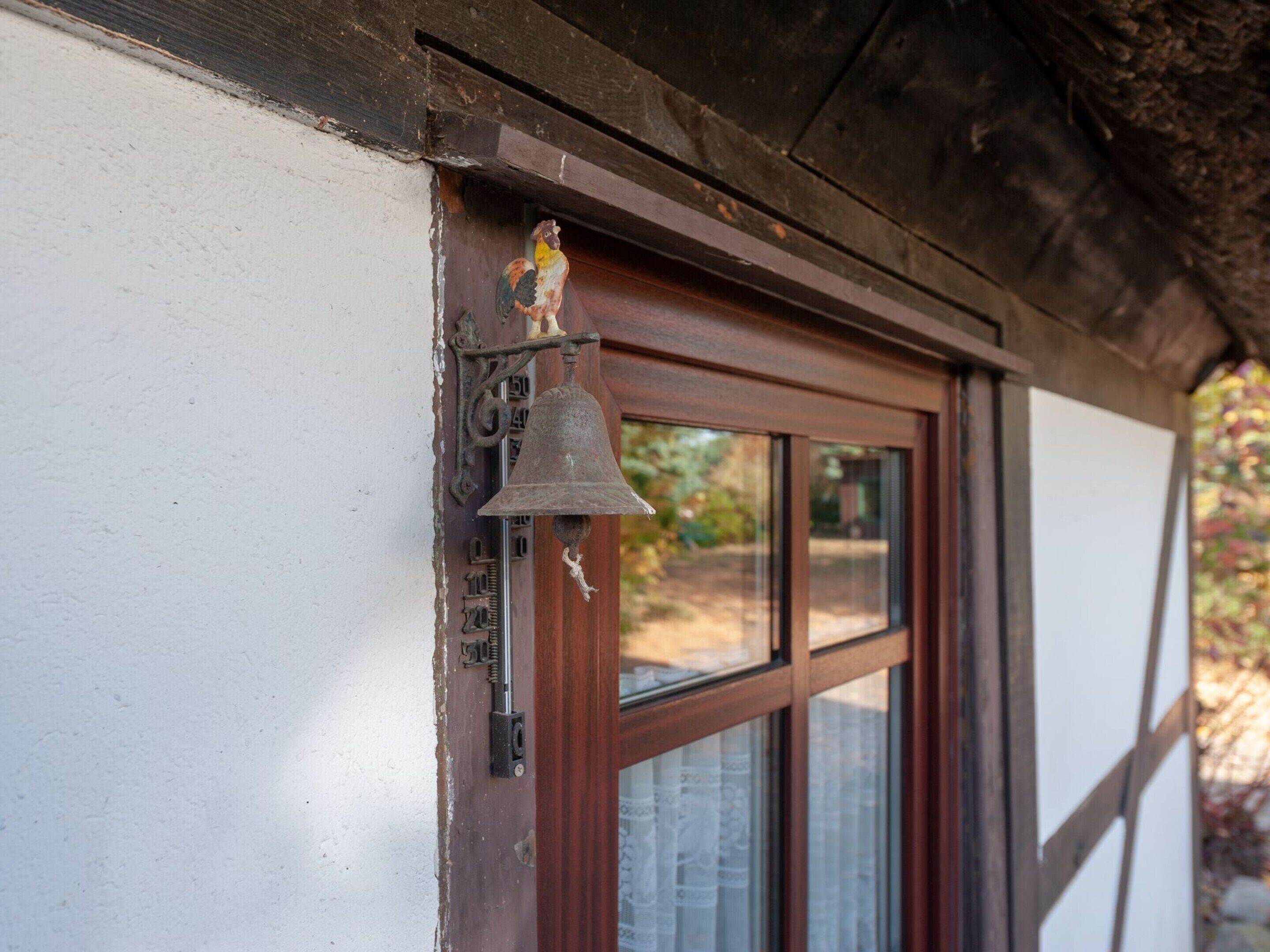 A wooden door with a bell and a small figurine.