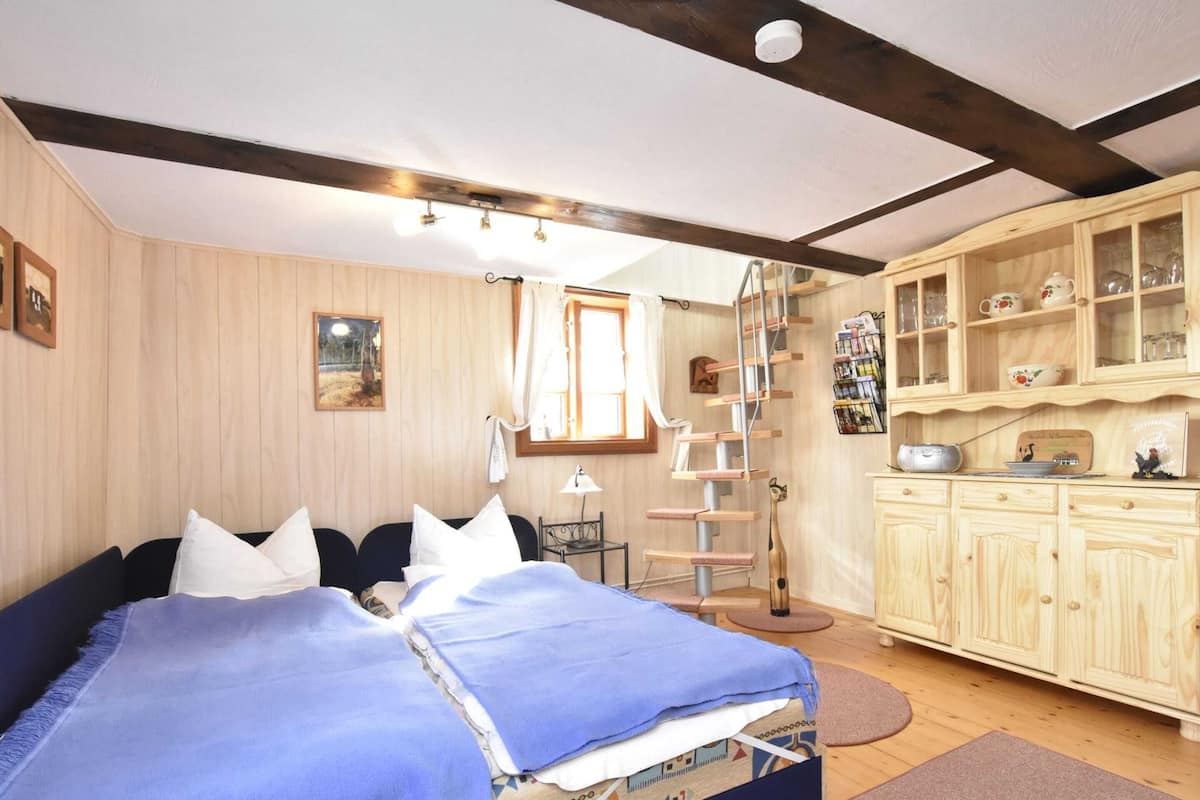 A bedroom with a bed, a wooden wardrobe, a cat tree, and a window.