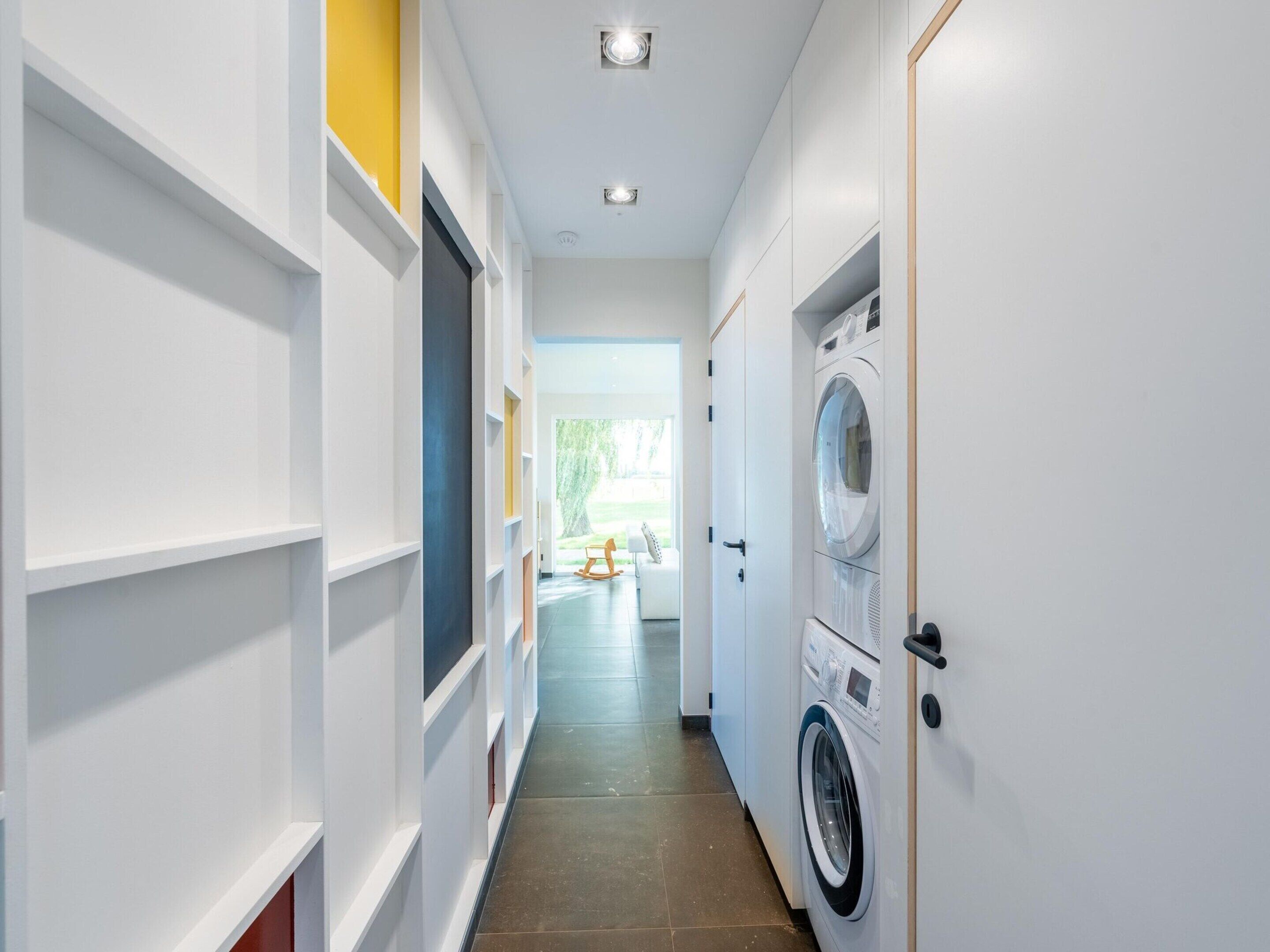 Une buanderie équipée d’un lave-linge et d’un sèche-linge, avec des murs blancs et un sol carrelé.