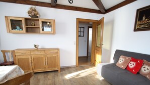 A room with wooden flooring, a wooden cabinet with glass doors, a dining table with chairs, and a grey sofa with decorative pillows. - Apartment in Sankt Johann im Pongau Near Ski Area (Sankt Johann im Pongau)