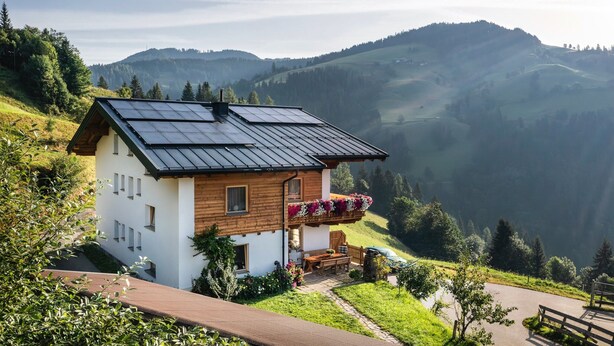 A house with solar panels, a wooden balcony with flowers, and a scenic mountain view. - Apartment in Sankt Johann im Pongau Near Ski Area (Sankt Johann im Pongau)