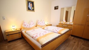 A bedroom with a wooden bed, two bedside tables, a nightstand, a mirror, and a wardrobe. - Apartment in Sankt Johann im Pongau Near Ski Area (Sankt Johann im Pongau)