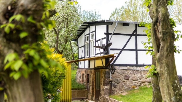 Un bâtiment traditionnel à colombages, doté d’un petit jardin, d’un sentier et d’une statue.