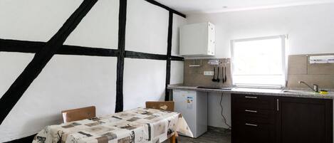 A kitchen with a table set for two, a window, and a modern appliance.