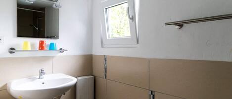 A bathroom with a white sink, a mirror, a window, and a towel rack.